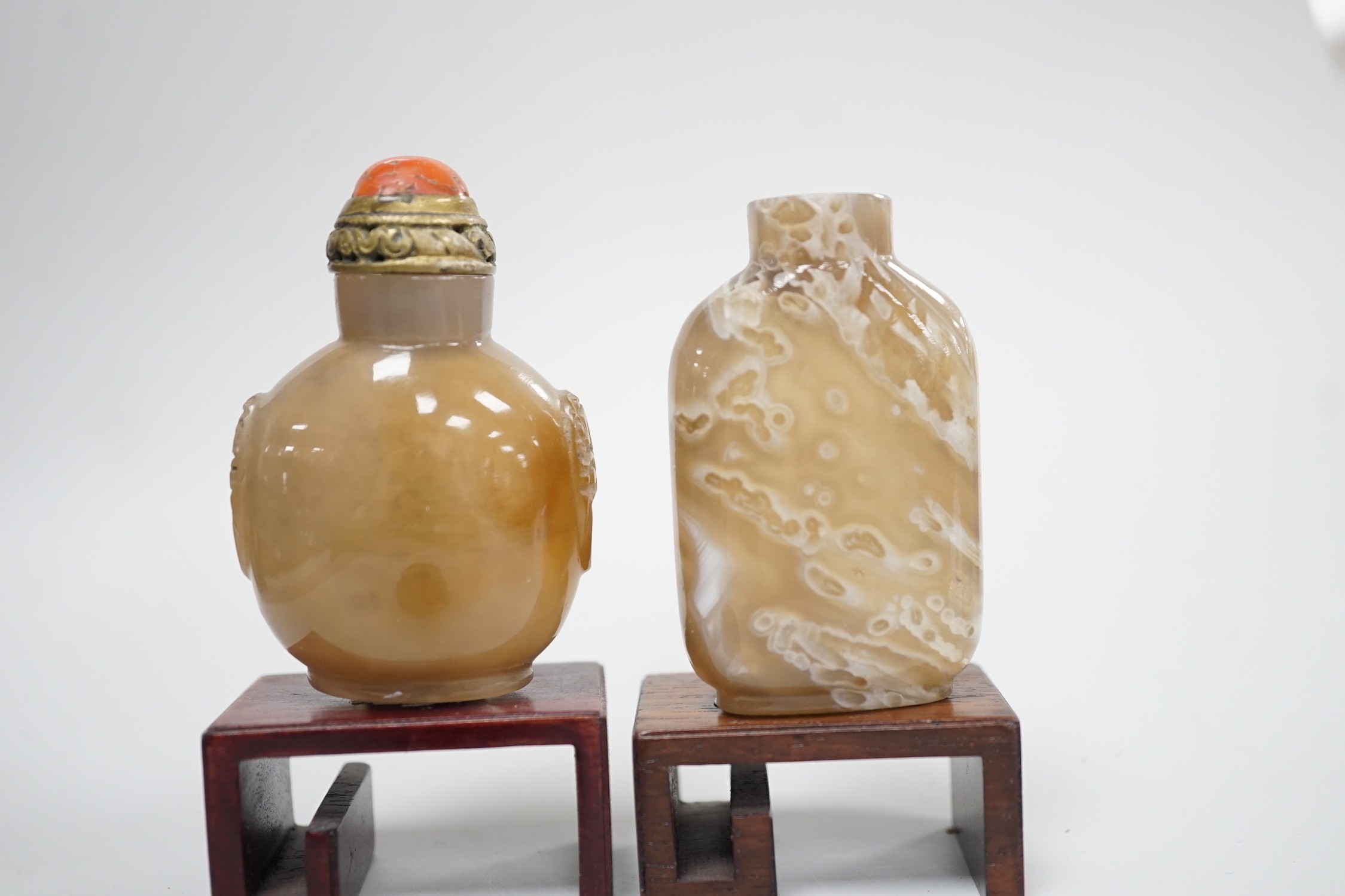 A Chinese chalcedony dendritic chalcedony (macaroni agate) snuff bottle, 5.7cm and a honey coloured agate mask and ring handled snuff bottle, 4.7cm, brass and coral stopper, both 1780-1880, together with a cameo agate pi